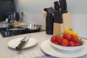 a bowl of tomatoes on a kitchen counter with a knife at MOKA Living-Sunset Apt, Nordic Design,Küche,WLAN, SmartTV in Magdeburg +20 photos