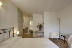 biała sypialnia z łóżkiem, stołem i krzesłami w obiekcie Rosa dei Venti - Lake view Apartments & Suites w mieście Bellano