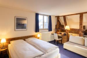 a bedroom with a bed and a desk and a chair at Sorell Hotel Rüden in Schaffhausen