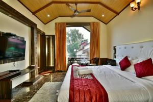 a bedroom with a large bed and a flat screen tv at Dalhousie valley Resort By DLS Hotels in Banikhet