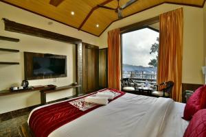 a bedroom with a large bed with a large window at Dalhousie valley Resort By DLS Hotels in Banikhet