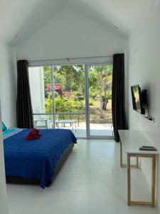 a bedroom with a blue bed and a sliding glass door at Mook Ing Lay in Koh Mook