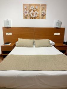 una camera da letto con un grande letto bianco con due luci di Pensión Residencia Fornos a Santiago de Compostela