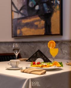 a table with a plate of food and a glass of orange juice at Ador Hotel North Mitrovica in Mitrovicë