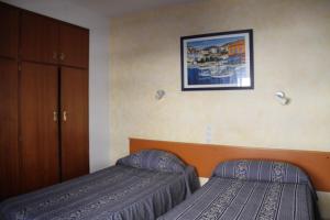 Una habitación de hotel con dos camas y un cuadro en la pared. en Hostal Mengual, en Gandía