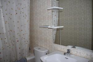 Un baño con lavabo, espejo e inodoro. en Hostal Mengual, en Gandía