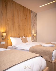 two beds in a hotel room with wooden walls at Ador Hotel North Mitrovica in Mitrovicë