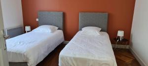 2 camas en una habitación con paredes de color naranja en Résidence Auger en Bourges