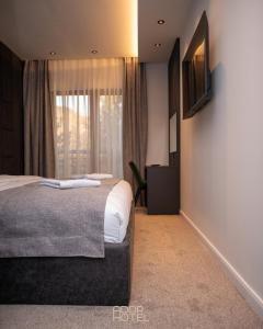 a bedroom with a bed and a television on a wall at Ador Hotel North Mitrovica in Mitrovicë