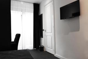 1 dormitorio con TV en la pared y puerta en Sara's Boutique Hotel, en Ámsterdam