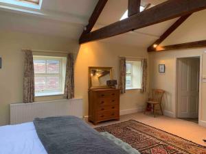 a bedroom with a bed and a dresser and windows at The Old Granary at Red House Farm in Ripon