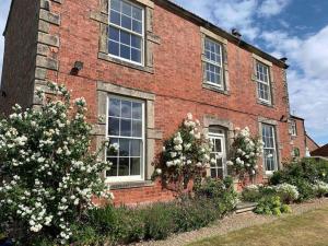 a brick building with windows and flowers in front of it at The Old Granary at Red House Farm in Ripon