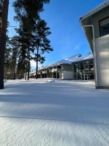 a building in the snow with trees in the background at Saimaanranta Resort by Anttolanhovi in Mikkeli