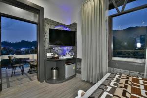 a bedroom with a large window and a television at Dalhousie valley Resort By DLS Hotels in Banikhet