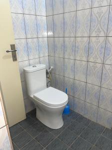 La salle de bains est pourvue de toilettes et d'un mur carrelé. dans l'établissement KADIDJA APARTMENTS & SUITES Akodessewa, à Lomé