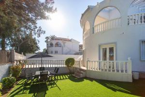 a house with a yard with chairs and an umbrella at CH Villa Golf Park La Marquesa in Rojales