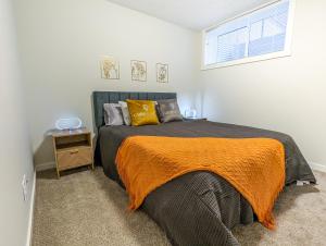 a bedroom with a bed with an orange blanket and a window at GLOBALSTAY New Apartments in Cranbrook Free street parking in Calgary