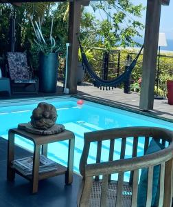 a statue sitting on a table next to a chair next to a pool at Suite INDIGO JACUZZI PRIVE PISCINE VUE MER acces cuisine laverie in Saint-Pierre