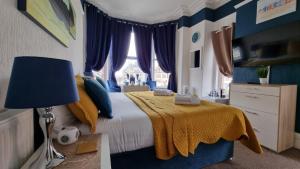 a bedroom with a bed with a yellow blanket and blue curtains at The Tilstone Guest House in Llandudno