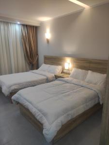 two beds in a hotel room with two lamps at You are welcome to Mido Shallet in Naqādah