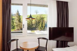 een hotelkamer met een tafel en stoelen en een raam bij Tailormade Hotel RIGIBLICK Küssnacht in Küssnacht
