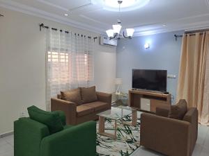 ein Wohnzimmer mit einem Sofa und einem TV in der Unterkunft Spetiv Guesthouse in Douala