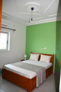 um quarto com uma cama com paredes verdes em Spetiv Guesthouse em Douala