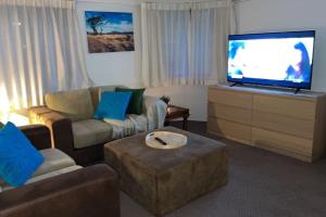 sala de estar con sofá y TV de pantalla plana en 2 Beds 2 Baths Apt In Braddon CBD - Pool, 1 Free Parking, Gym, en Canberra