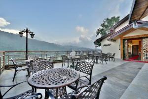 a patio with tables and chairs on a balcony at Dalhousie valley Resort By DLS Hotels in Banikhet