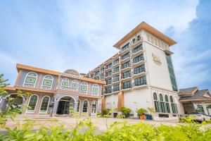 a large hotel with a white building with green windows at Mekong Heritage Hotel in Nakhon Phanom