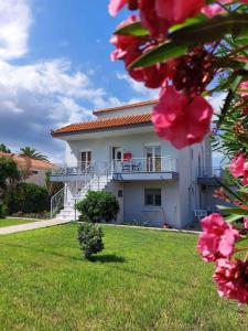 una casa blanca con un patio con flores rosas en Δειλινά, en Plati
