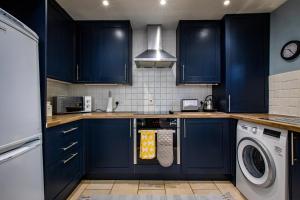 cocina con armarios azules, lavadora y secadora en Carr Croft Lodge - Ilkley Centre en Ilkley
