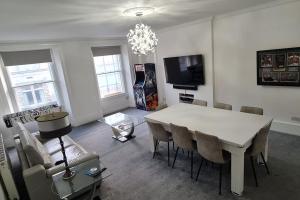 Large 4 bed (sleeps 8) Castle View في إدنبرة: غرفة معيشة مع طاولة وكراسي بيضاء