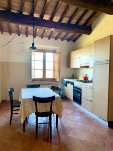 een keuken met een tafel en stoelen en een witte koelkast bij Appartamento con vista panoramica in Campagnatico
