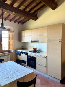 uma cozinha com armários brancos e uma mesa com uma chaleira. em Appartamento con vista panoramica em Campagnatico