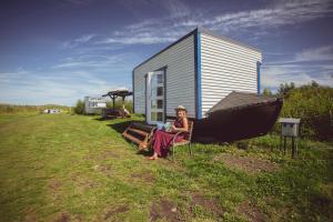 Varnja的住宿－Lake Peipsi boathouses，坐在房子前椅子上的女人