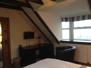 a bedroom with a bed and a desk and two windows at Lochend Farmhouse in Aberdeen