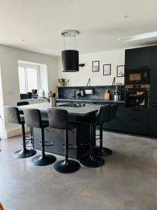 een keuken met zwarte kasten en een tafel en stoelen bij Malie & Macha - Jolie Maison à Malo-les-Bains in Duinkerke