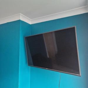 a flat screen tv hanging on a blue wall at Belfast City house in Belfast