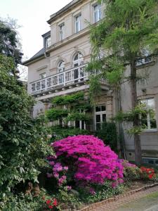 un bâtiment avec des fleurs roses devant lui dans l'établissement Am Elbradweg - Nichtraucher-Gästezimmer Weiland, à Dresde