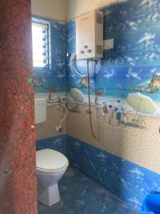 a bathroom with a toilet and a painting of a beach at NeelRatna Bed And Breakfast in Shirdi