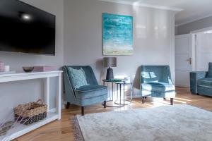 - un salon avec 2 chaises bleues et une télévision dans l'établissement Haus Boy, à Kampen