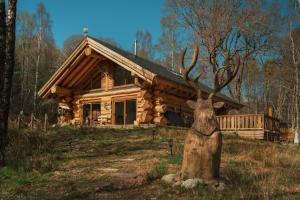 a statue of a deer head in front of a log cabin at Caledonian Cabin in Invergarry