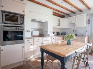 a kitchen with white cabinets and a wooden table at Stag Cottage in Penrith