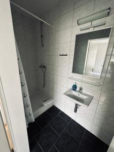 ein Badezimmer mit einem Waschbecken, einem Spiegel und einer Badewanne in der Unterkunft Gästehaus Hanseat in Bremerhaven