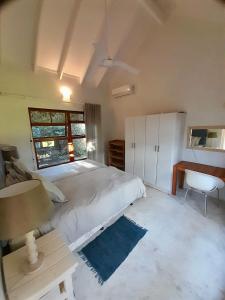 a bedroom with a large white bed and a desk at Bush house by the sea, Ponta Malongane in Ponta Malongane