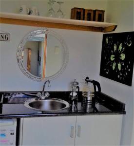 un bancone della cucina con lavandino e specchio di Bush house by the sea, Ponta Malongane a Ponta Malangane