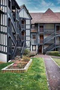 a building with stairs and a courtyard with grass at L'Hippique C.L.S Deauville in Deauville