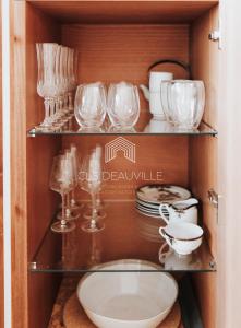 a cupboard with glass dishes and plates in it at L'Hippique C.L.S Deauville in Deauville