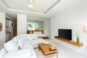 a living room with a white couch and a tv at Chi Samui Resort in Bophut